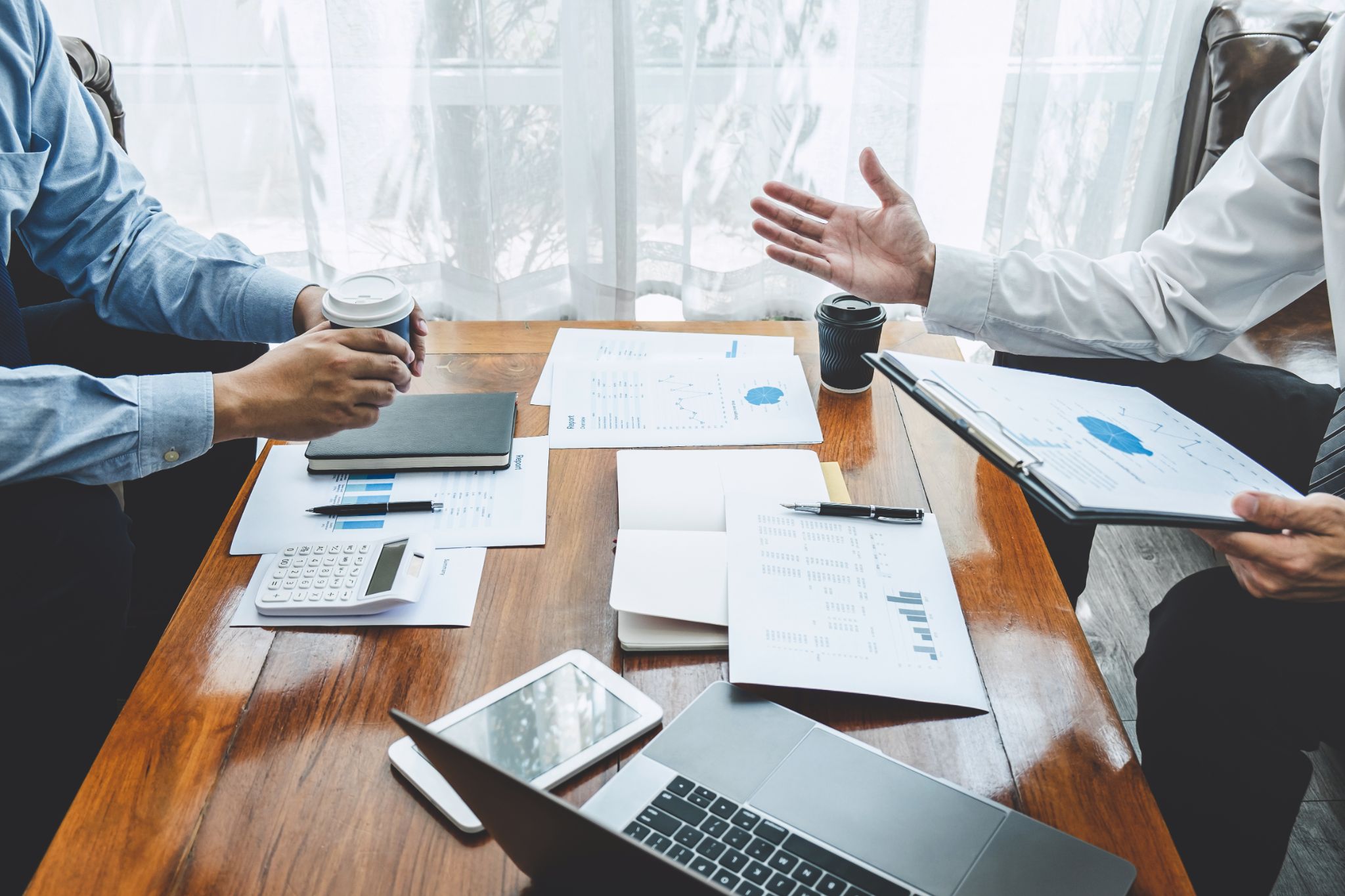 Two businessmen in suits sitting across a table from each other intensely discussing a pile of papers with finances on them. Our embezzlement lawyers in Houston understand the severity of embezzlement accusations and will thoroughly investigate charges to create a personalized defense.